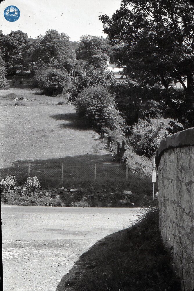 Road over canal bridge looking towards road junction with bus stop