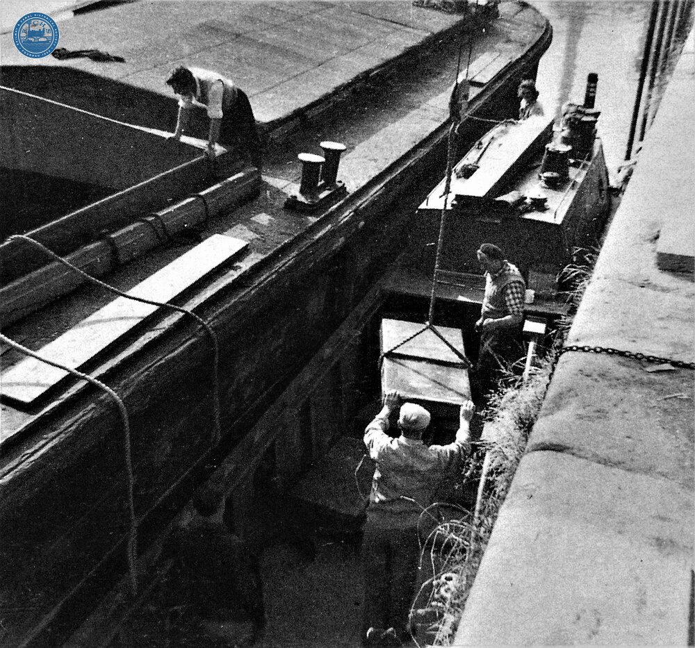 Four NB had descended Anderton Lift to receive load of copper ingots; a view of ingots being loaded into Keppel by a mobile crane supervised by captain Jack Tolley. 1961