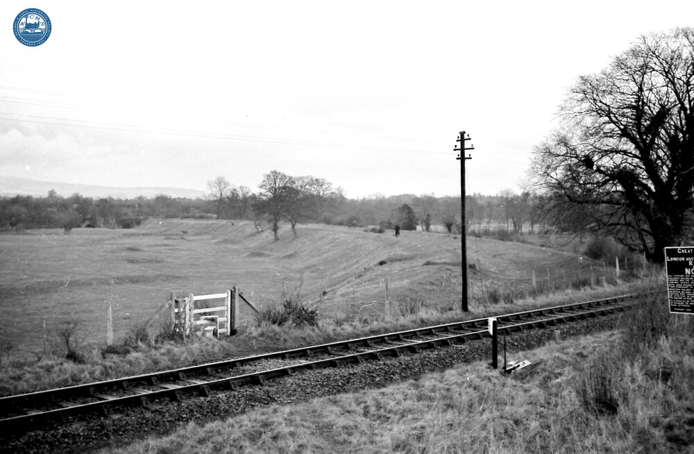 Leominster Canal. Near Brimfield. Abandoned canal bed, looking North. Railway crossing onto embankment towards the Teme aqueduct. 1954 or 1957