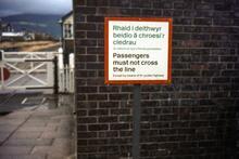 Barmouth station (DJP @ 100m 50ch). Bilingual crossing the line notice. 10 September 1983