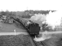 Corby Ironstone Railways. On the Deene Park line, close to Weldon Lodge, looking east.  Engine 63 + 15 empty wagons. 14 April 1963