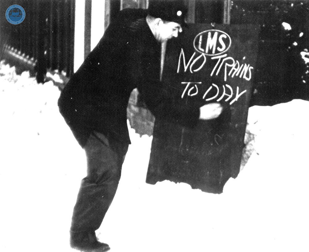 LMS Station Porter writing public notice that no trains are running - because of deep snow. (Ref: 031345)
